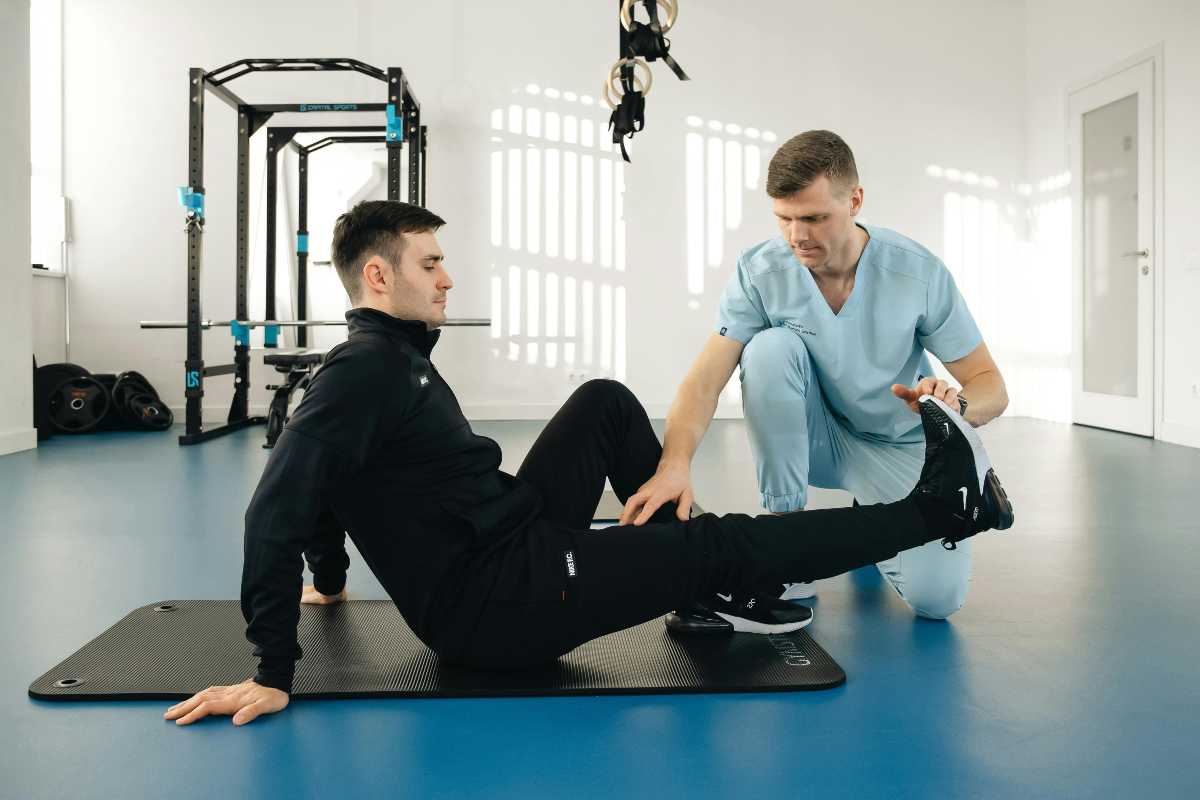 Barbat facand exercitii de recuperare, fizioterapeut, sala de sport